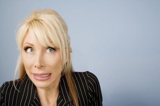 Close Up of an Apprehensive blonde businesswoman in front of a blue background