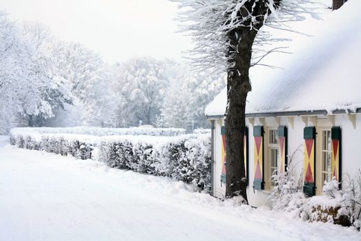 A country road, covered with snow, small farmers house