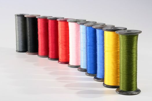 Colour threads for an embroidery on a white background. Threads on coils for industrial use.