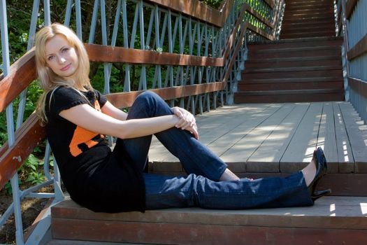 The beautiful girl sits at ladder steps