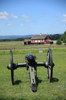 Farm house and cannon on Cemetery Ridge overlook battle site at Gettysburg National Military Park