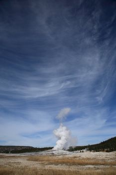 Old Faithful Geyser erupting under a big sky