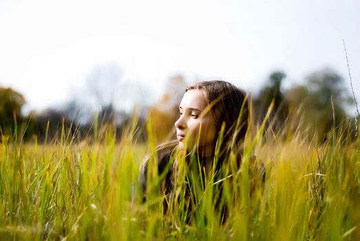 dreaming beautiful girl lying in a meadow. view through the grass 