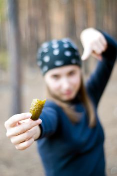 girl in the woods with a cucumber in her right hand. focus on cucumber