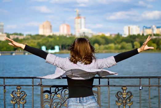 flying girl on the shore of the city pond with a flowing shirt