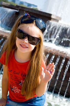 smiling little girl in two glasses near the fountain