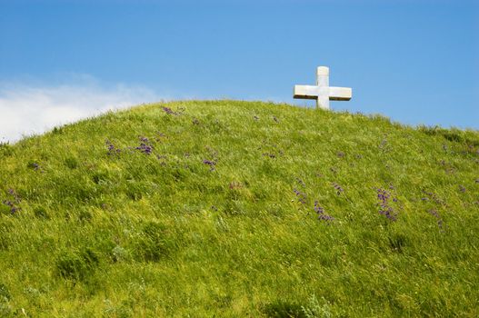 christian cross on the top of green hill