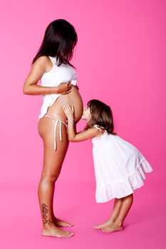 Little girl hugging and kissing her mother belly

