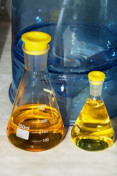 Erlenmeyer flasks with yellow liquid in chemistry lab (blue background)