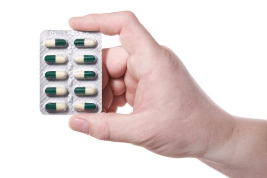 Hand holds a package with green-white pills.  Isolated on white [with clipping path].