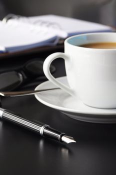 coffee and organizer in a black table showing break or breakfast in office