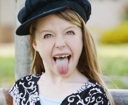 Close up of a young girl wearing a cap sticking out her tongue