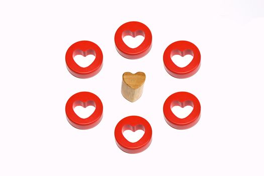 single wooden heart surrounded by six red hearts