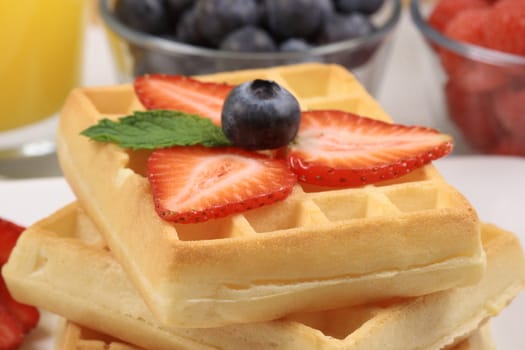 Exquisite belgian waffle garnished with organic strawberry and blueberry