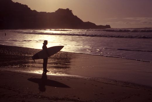 A silhouette of an early morning surfer on a beautiful shoreline.