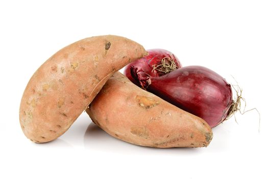 Two raw unpeeled red onions and sweet potato on a reflective white backgrounds