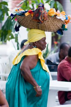 Aged african woman in traditional clothing with basket on the head. January 2008, Santiago, Cuba.