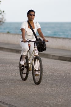Woman in white riding old bicycle. January 2008, Baracoa, Cuba.