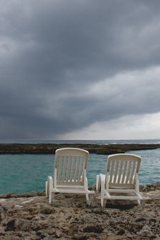 Two lonely chairs on the beach at a rainy day