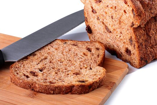 Slice of the cut off bread with a knife on a kitchen board.