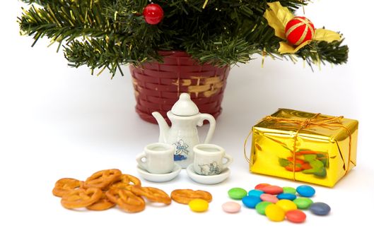 small teapot with two cups, varicoloured sweetmeat and baking under cristmas fir tree