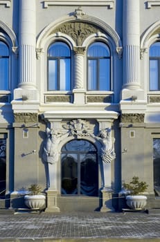 part of facade of the old-time building with statue of the woman and men and pillar