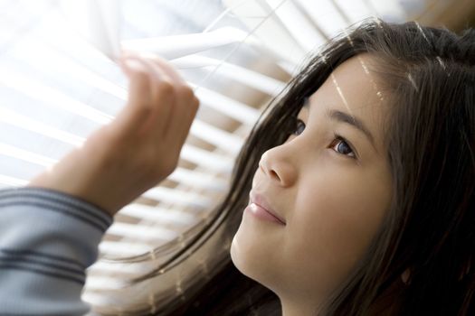 Girl looking out window through blinds