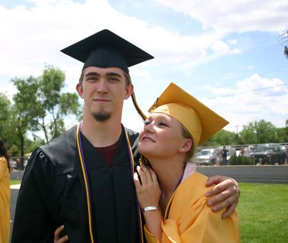 Two attractive young graduates in their caps and gowns look toward the future.