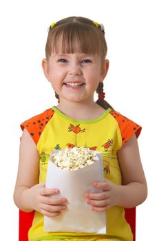 little girl sits on chair, smiles and keeps package with popcorn