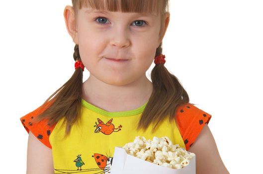 little girl sits on chair, smiles and keeps package with popcorn