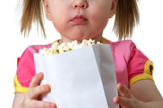 little girl sits on chair, smiles and keeps package with popcorn