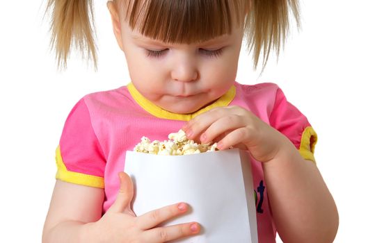 little girl sits on chair, smiles and keeps package with popcorn