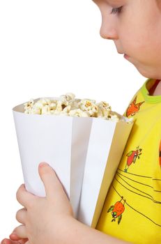 little girl sits on chair and keeps package with popcorn