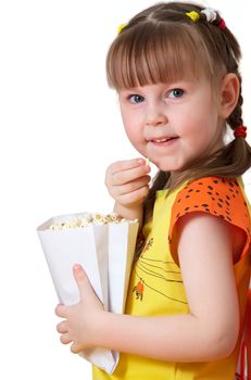 little girl sits on chair, smiles and keeps package with popcorn 