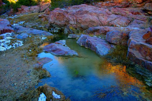 The ice-encrusted water of Grape Creek reflects the winter sun rising from the granite bluffs above, creating a momentary fantasy landscape of blues and golds.