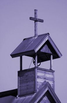 Rustic wooden cross on ancient desert church still calls worshipers to services.