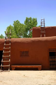 Two hand-made ladders lean against adobe hacienda