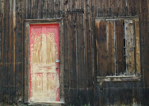 A red door, with paint peeling, on an ancient abandoned building in a Colorado ghost town.