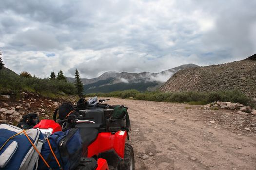 ATV parked on side of misty high altitude trail in the Colorado Rocky Mountains.