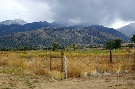 Autumn storm coming in over the mountains with snow clouds beginning to drape over the peaks.  Foliage in the valley is just beginning to show its fall colors