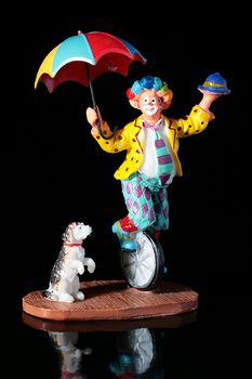Circus theme, the cheerful clown on a bicycle with a colour umbrella and nearby a dog.