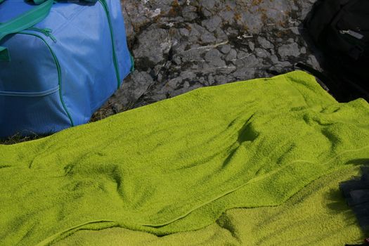 towel and beach bag lain on the ground while the owner is out cooling in the water.