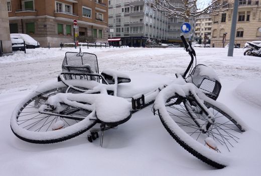 Fallen bicycle covered by snow in the street