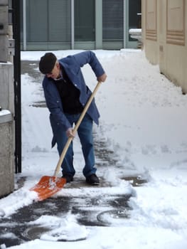 Old man removing snow with a shovel