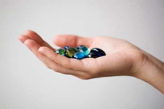 The hand holds round multi-coloured slices of glass. Close-up. Shallow depth of field. 