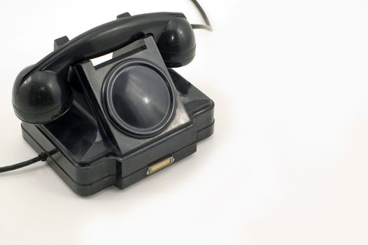 The old telephone of black colour on a white background.