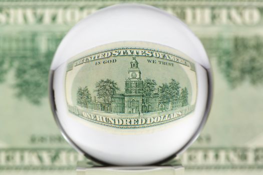 Hundred dollar banknote through glass sphere. Blur background.