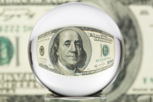 Hundred dollar banknote through glass sphere. Blur background.