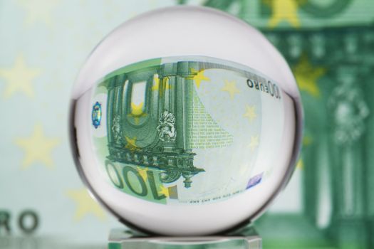 Hundred euro banknote through glass sphere. Blur background.