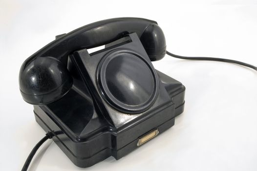 The old telephone of black colour on a white background.